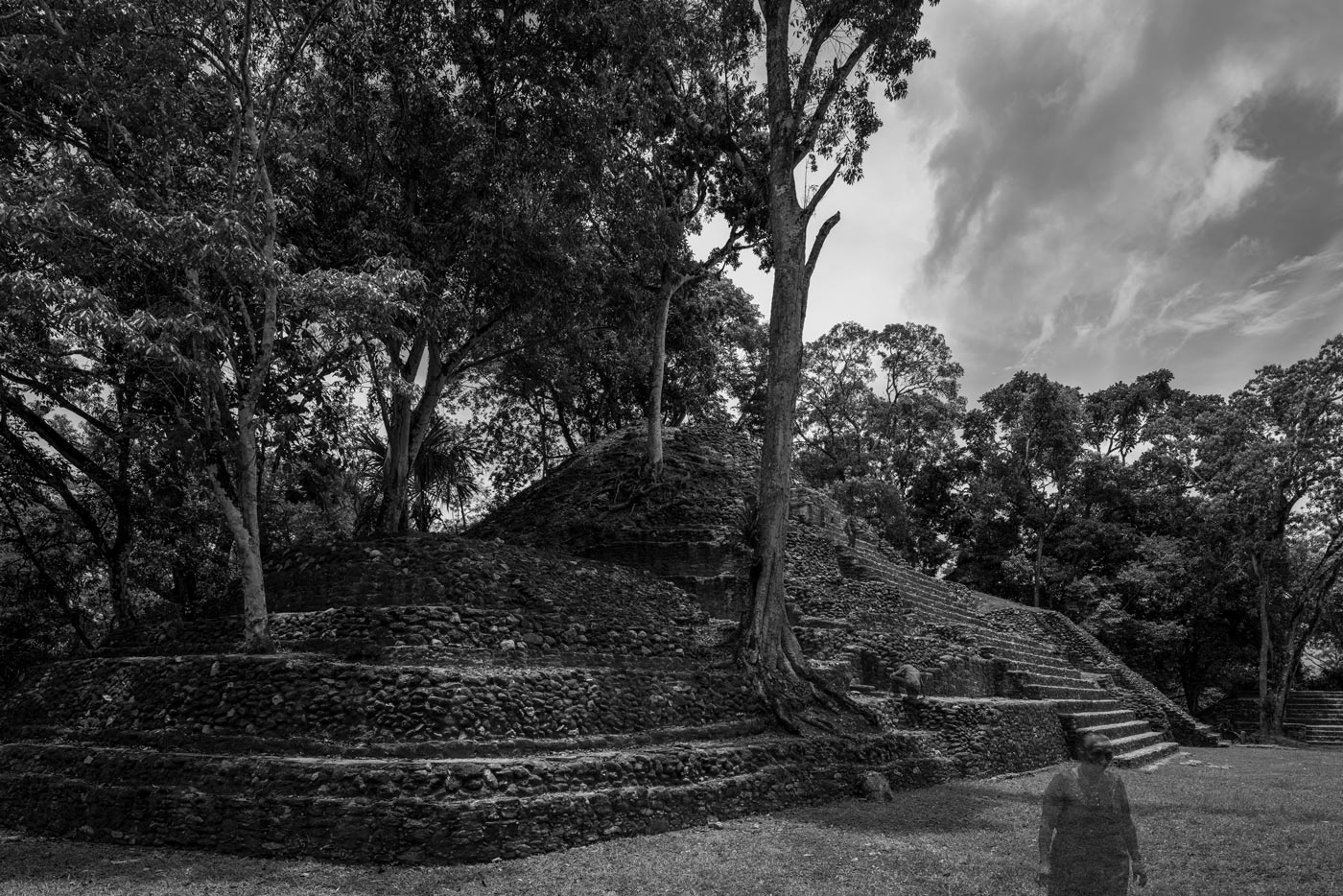 A translucent visitor before a stepped Maya structure at Cahal Pech
